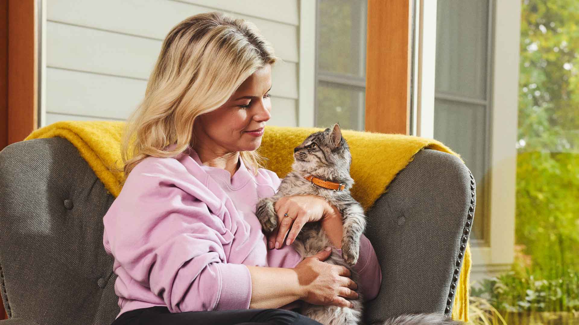A woman sitting in a chair and holding her cat