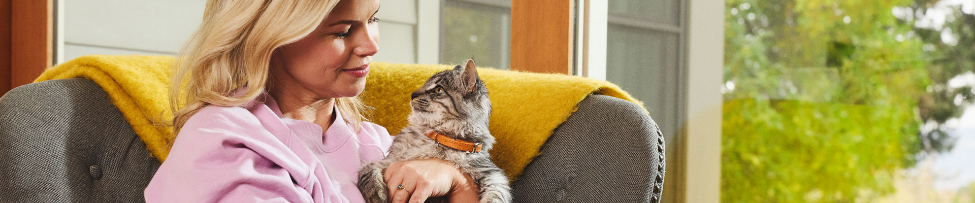 A woman sits in a patio chair holding a Maine Coon kitten